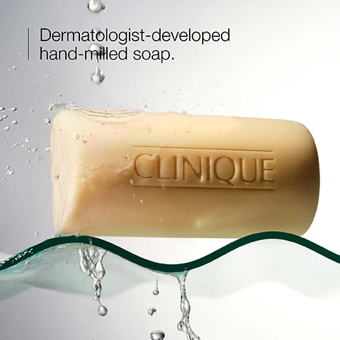Image 1 - A bar of beige soap labeled CLINIQUE is shown partially submerged in water with droplets splashing around it, accompanied by the text Dermatologist-developed hand-milled soap.
Image 2 - Image shows two bars of Clinique Facial Soap, one yellow labeled Clinique Facial Soap - Dry with the text Dermatologist-developed soap for dry skin and one beige labeled Clinique Facial Soap - Oily with the text Dermatologist-developed soap for oily skin.
